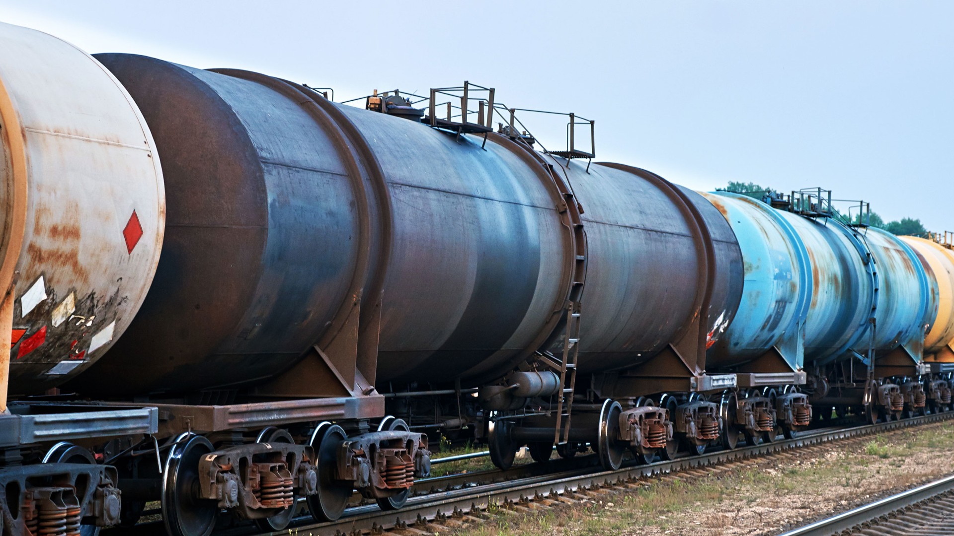 Train cars transporting various liquid materials.