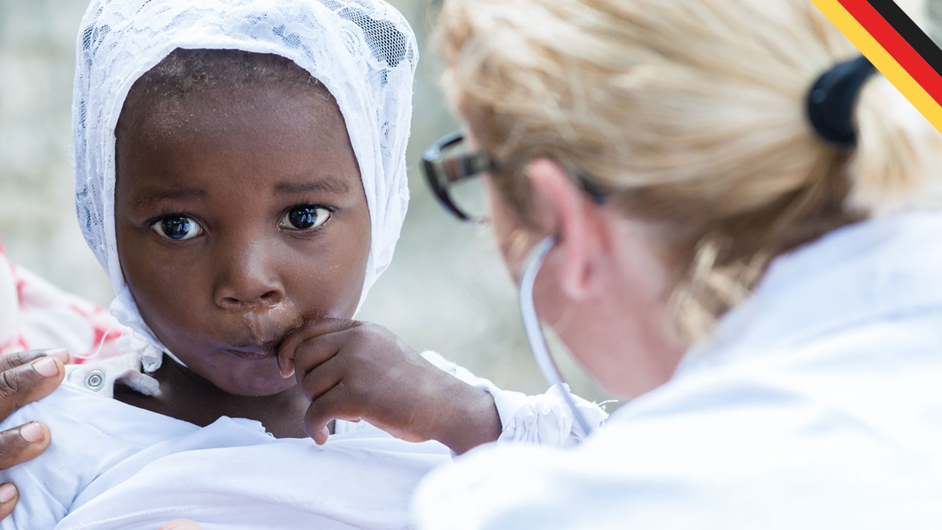 Child with mother receiving medical attention outdoors.